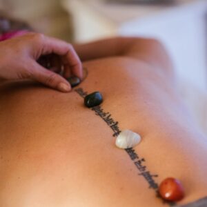 Crop masseuse putting stones on back of client