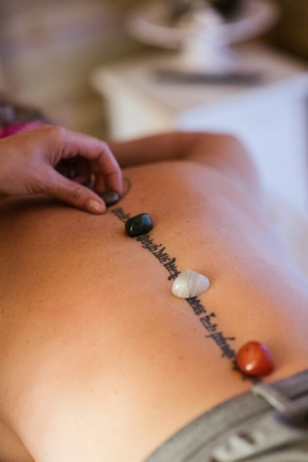 Crop masseuse putting stones on back of client